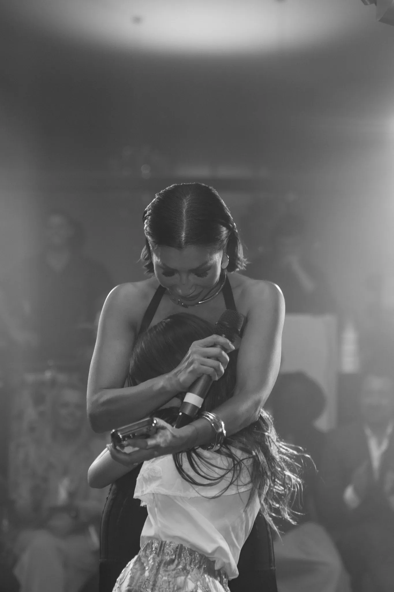 A singer embracing a guest during a live performance, in black and white
