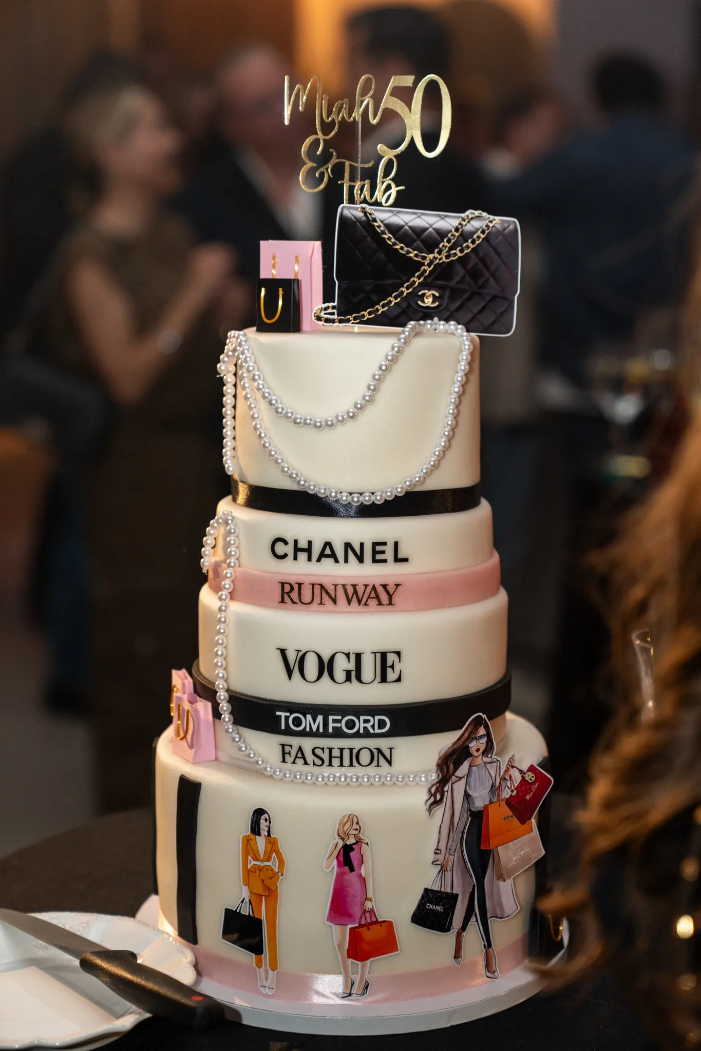 A tiered fashion-themed 50th birthday cake with a gold topper